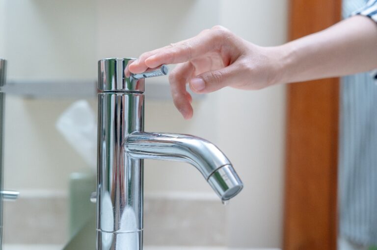 Eine Hand hält einen Wasserhahn zu